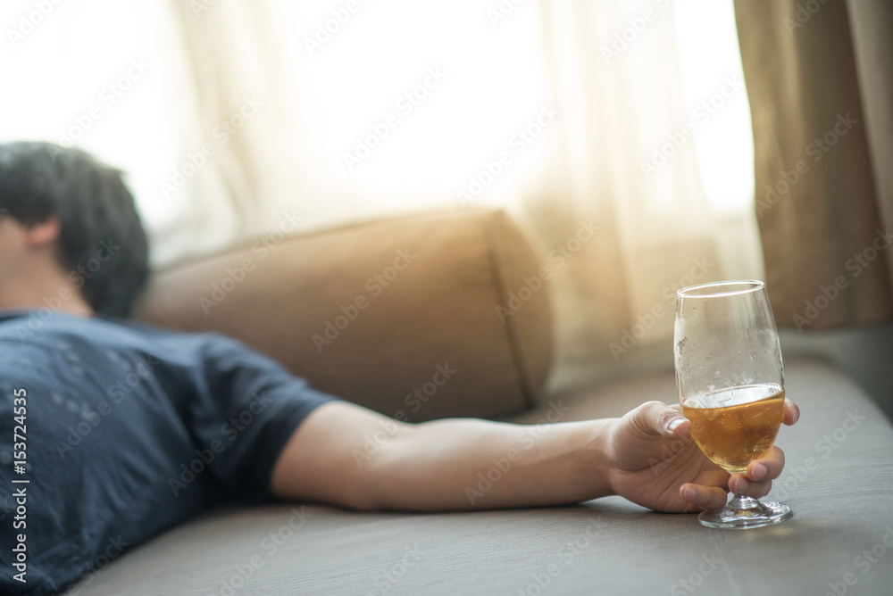 drunken man sleeping while holding a glass of beer in bedroom, hangover after holiday party, alcoholism or alcohol addiction concepts drunken man sleeping while holding a glass of beer in bedroom, hangover after holiday party, alcoholism or alcohol addiction concepts