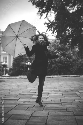 A woman in a European city  walks in a black coat at autumn and examines the neighborhood
 photo