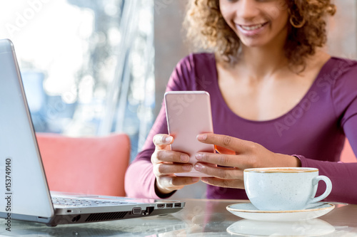 Female using her smartphone over a cup of coffee 