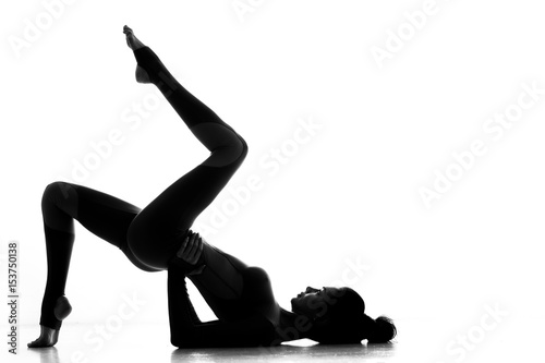 She is a stunner. Silhouette of a graceful gymnast posing with her fit and toned perfectly shaped body isolated on white