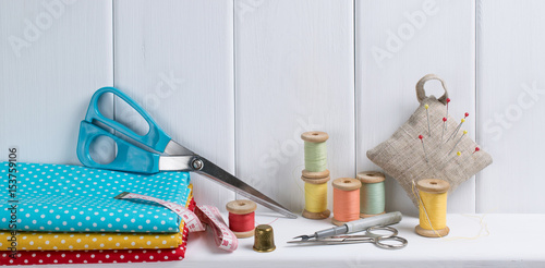 Set of tools for sewing and fabric lying on the wooden shelf. Interior design for seamstress.