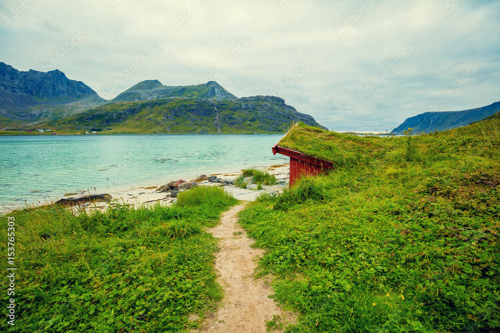 Fjord in rainy weather. Rocky beach in evening, Fishing house on the beach. Beautiful nature of Norway. Lofoten islands