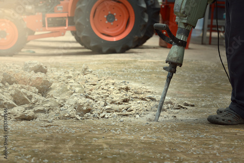 Builder Builder with pneumatic hammer drill equipment breaking asphalt at road