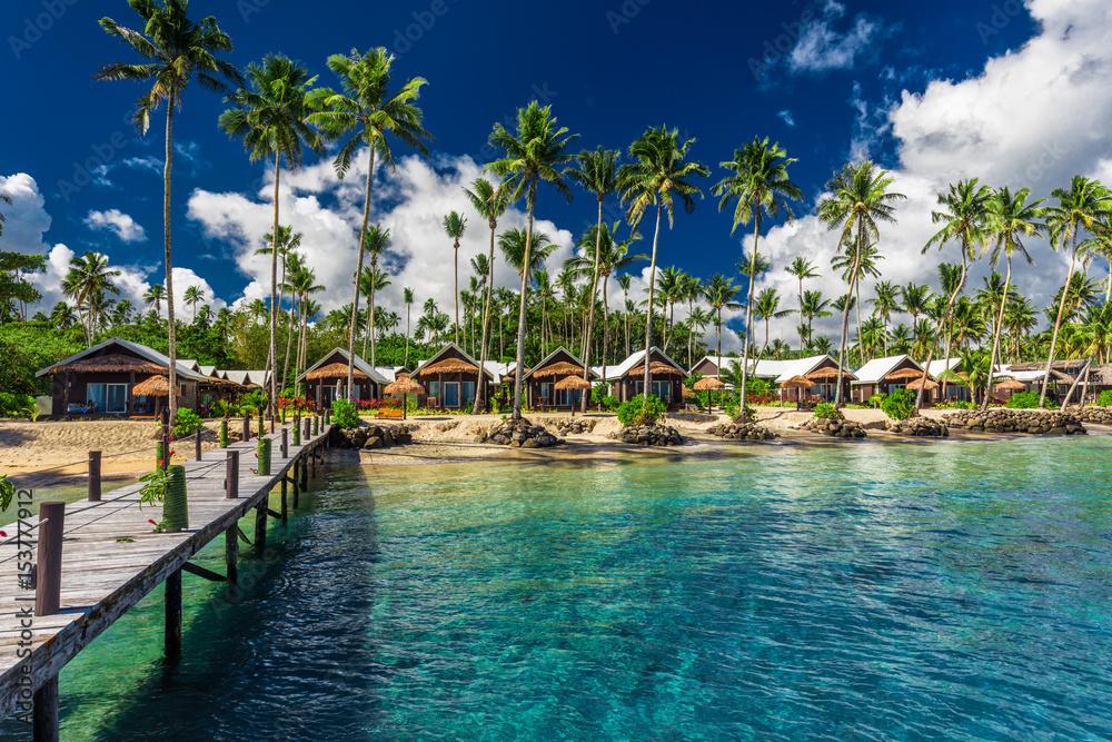 Tropical beach with with coconut palm trees and villas on Samoa Island