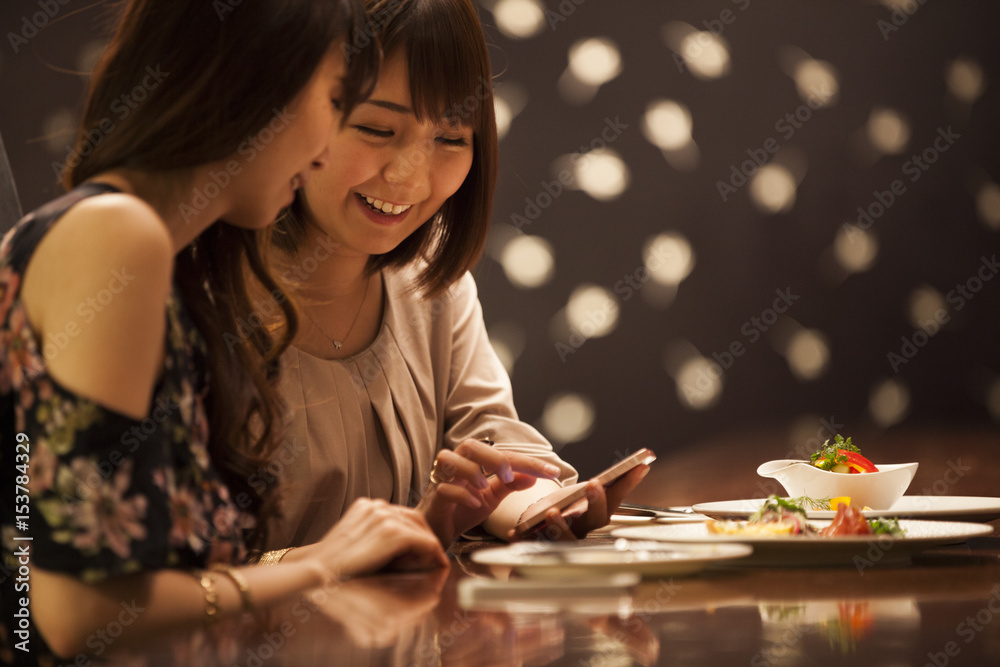 Fototapeta premium Women are watching smartphones while eating at the bar