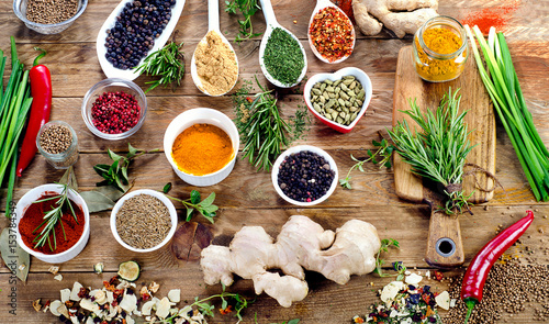 Various spices and fresh herbs on a rustic wooden background.