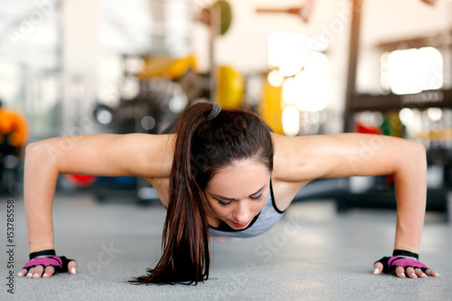 Young slender and pretty woman doing plank the gym. Concept of sport and healthy lifestyle