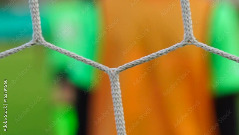 Soccer game seen through net, blurred view