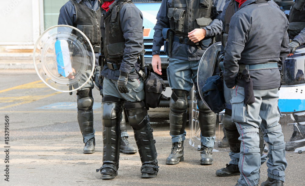 Group of anti-riot police officers with bullets and protective shields during security checks Group of anti-riot police officers with bullets and protective shields during security checks