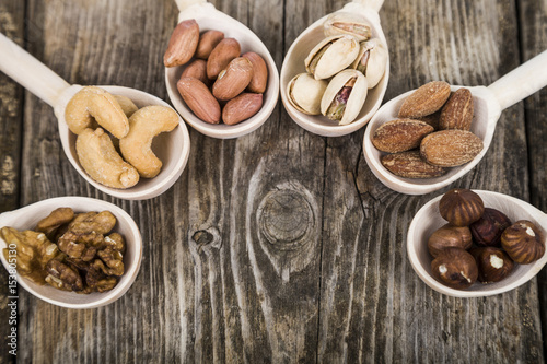 Nuts in a wooden spoons on a wooden table.