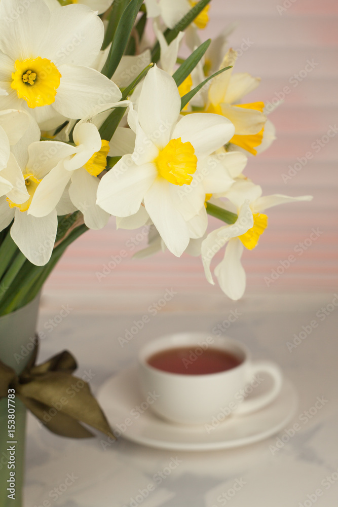 romantic date background; a cup of tea; yellow daffodils or narcissus In a bucket, selective focus, vertical