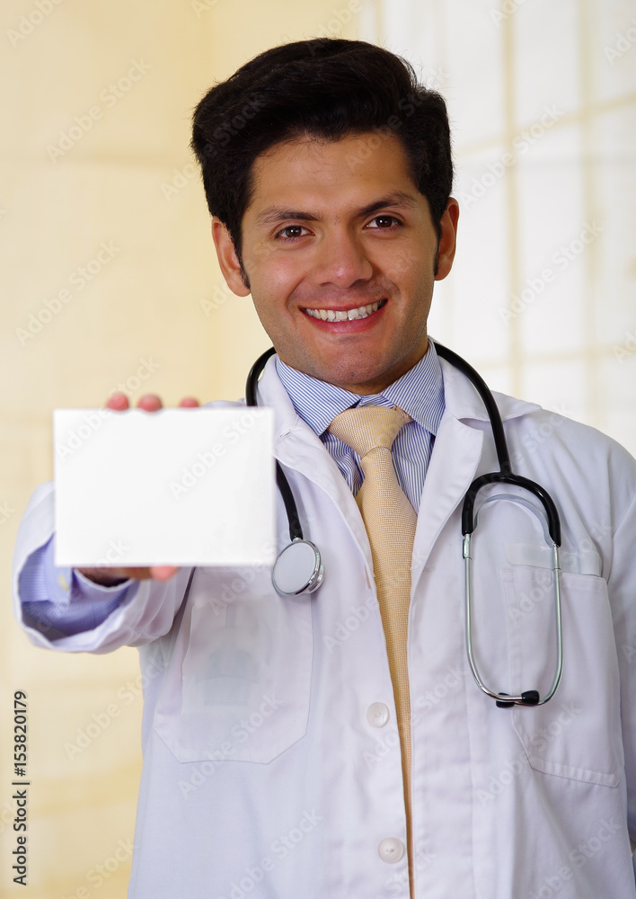 Confident handsome smiling doctor posing and looking at camera with an Stethoscope around his neck, pointing in from of him a medical prescription Confident handsome smiling doctor posing and looking at camera with an Stethoscope around his neck, pointing in from of him a medical prescription