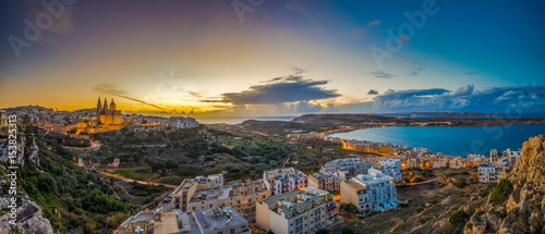 Il-Mellieha, Malta - Beautiful panoramic skyline view of Mellieha town at sunset with Paris Church and Mellieha beach at background with blue sky and clouds