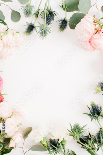 Round frame wreath made of red and beige rose flowers, eringium flower, eucalyptus branches and leaves isolated on white background. Flat lay, top view. Floral background