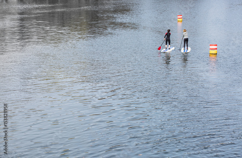 rippled water surface with two women standing on paddle boards