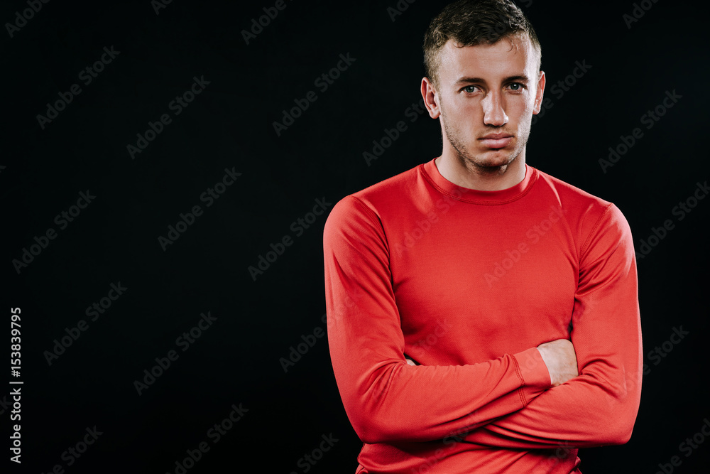 Handsome man wearing red sportswear and posing after exercises on dark background. Healthy inspirational fitness lifestyle, sport motivation. 