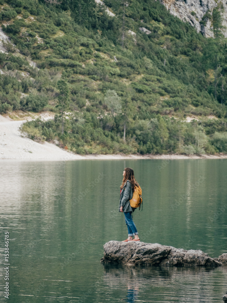 Female backpacker on stone in lake Female backpacker on stone in lake