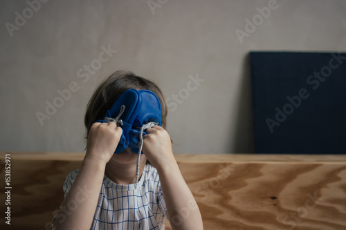 enfant qui joue avec des chaussons et se cache le visage