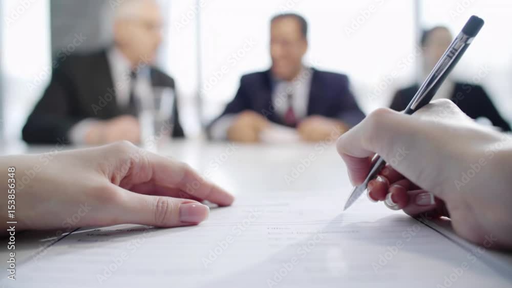 Closeup of hands of businesswoman filling out job application form while employers giving her new document for signing