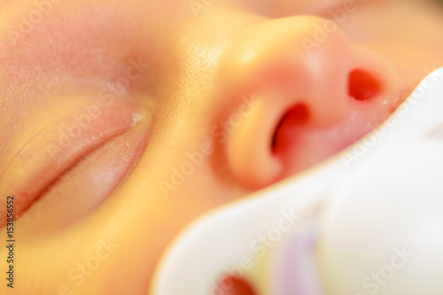 Closeup of little newborn sleeping with teat in mouth