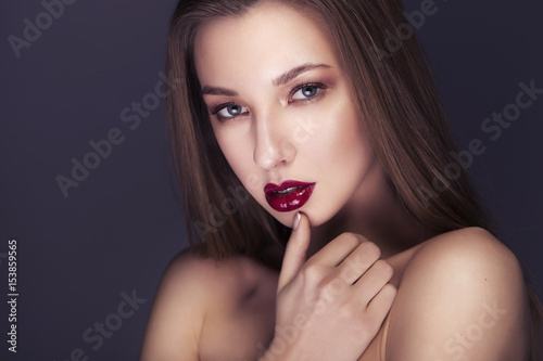 Beautiful sexy young brunette woman close up portrait with evening creative make up on a neutral dark background. Clean fresh skin