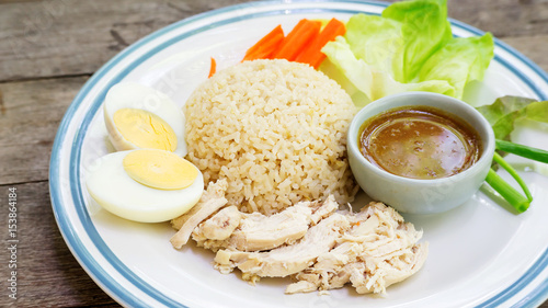 Hainanese chicken rice with boiled egg on a wooden table.