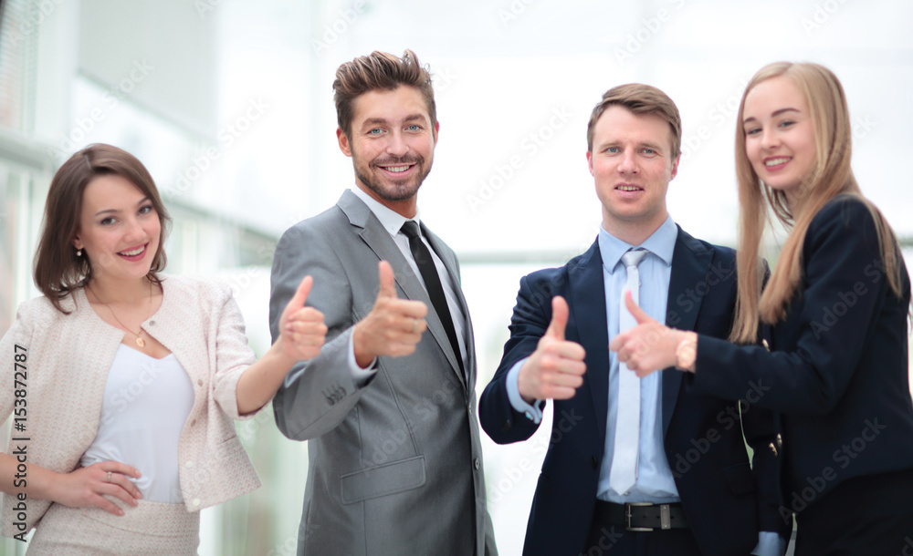 Business colleagues looking at camera and shoving thumbs up in t