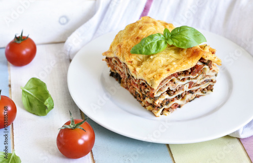 Fresh italian meat lasagne with cherry tomatoes. Italian pasta dish on a white plate.