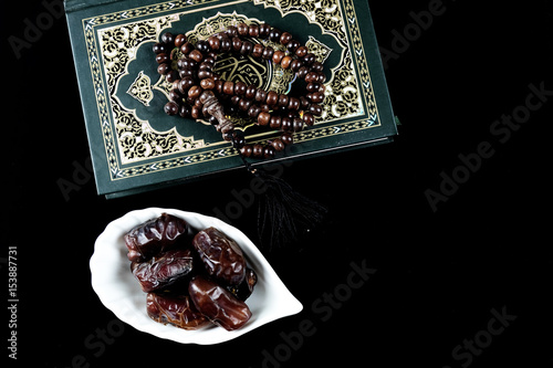 Kurma or Dried Dates, Holy Quran and rosary or tasbih with black background. photo