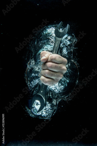 Male hand gripping wrench beneath water