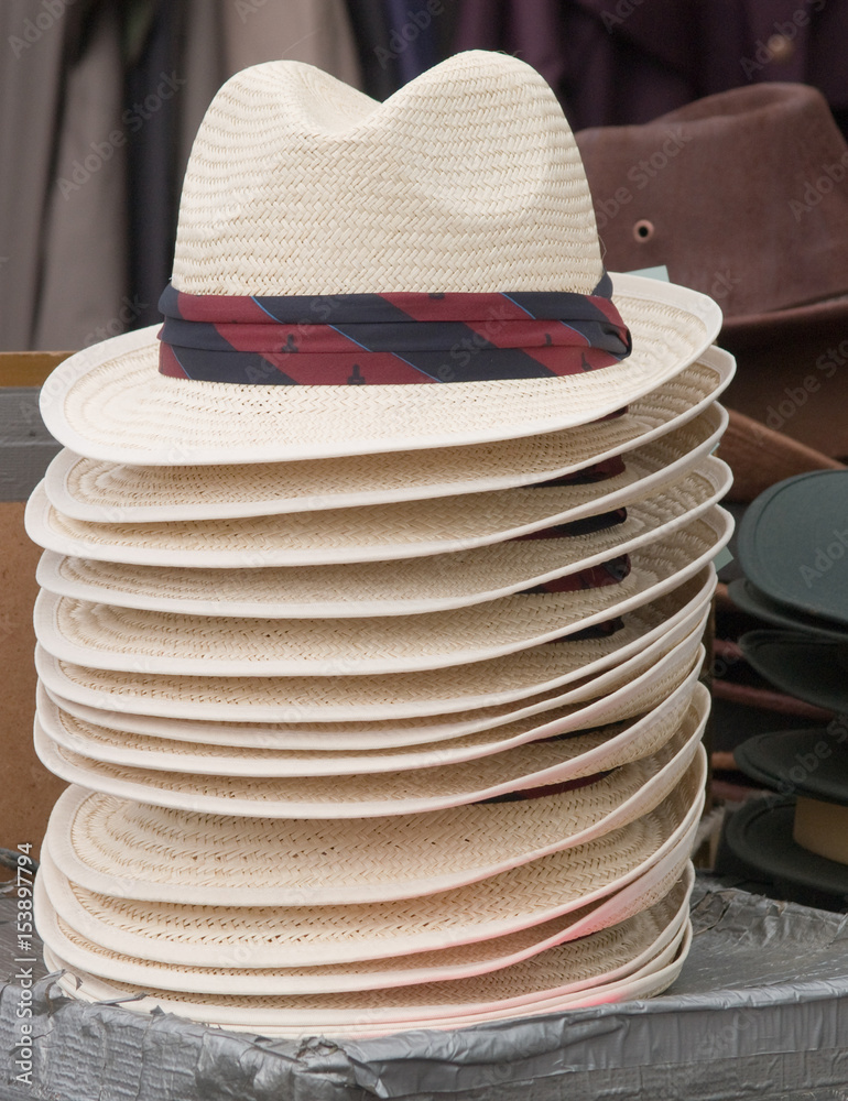 Straw fedora type hats with printed pattern hatband for sale on a stall at a country fair in the UK. Sometimes referred to as trilby, though  a true trilby has a shorter downturned brim at the front.