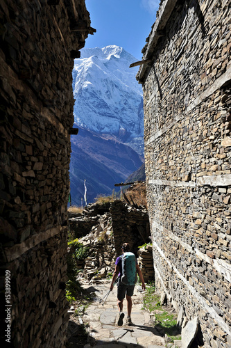 Woman treks through medieval stone buildings, Ghyaru, Nepal photo