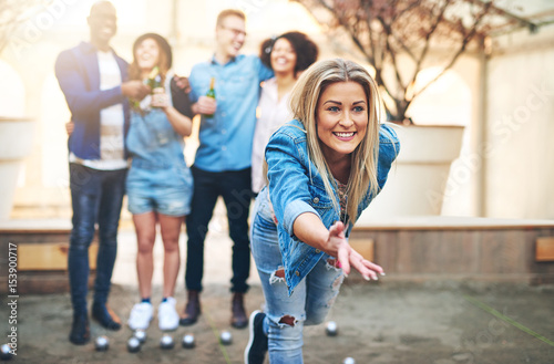 Woman throwing ball playing petanque and friends drinking beer