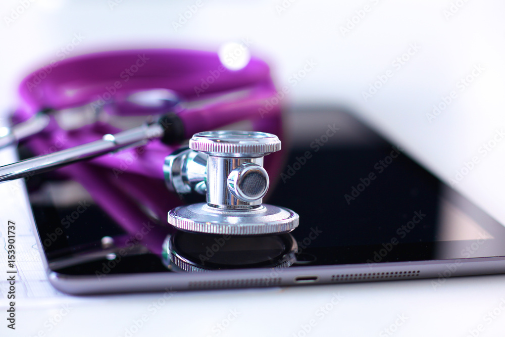 Tablet computer with a stethoscope lie on a table Tablet computer with a stethoscope lie on a table