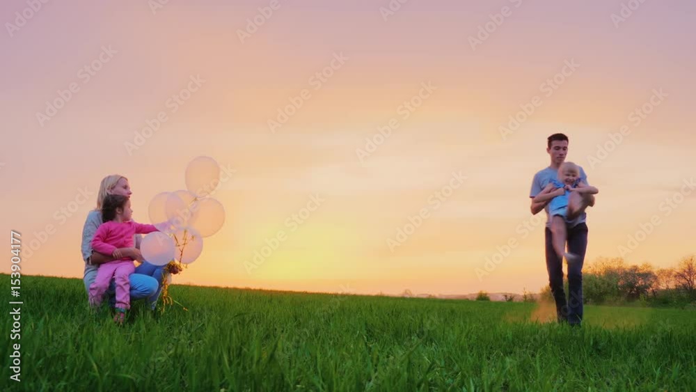 Mom and children are playing outside. The elder brother is circling his younger sister, the family having fun Mom and children are playing outside. The elder brother is circling his younger sister, the family having fun