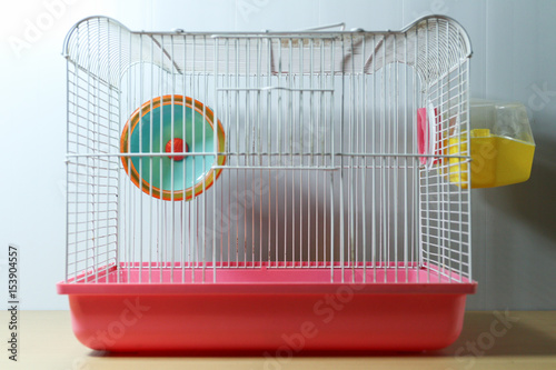 hamster wheel in old and empty hamster white and pink cage on wood desk