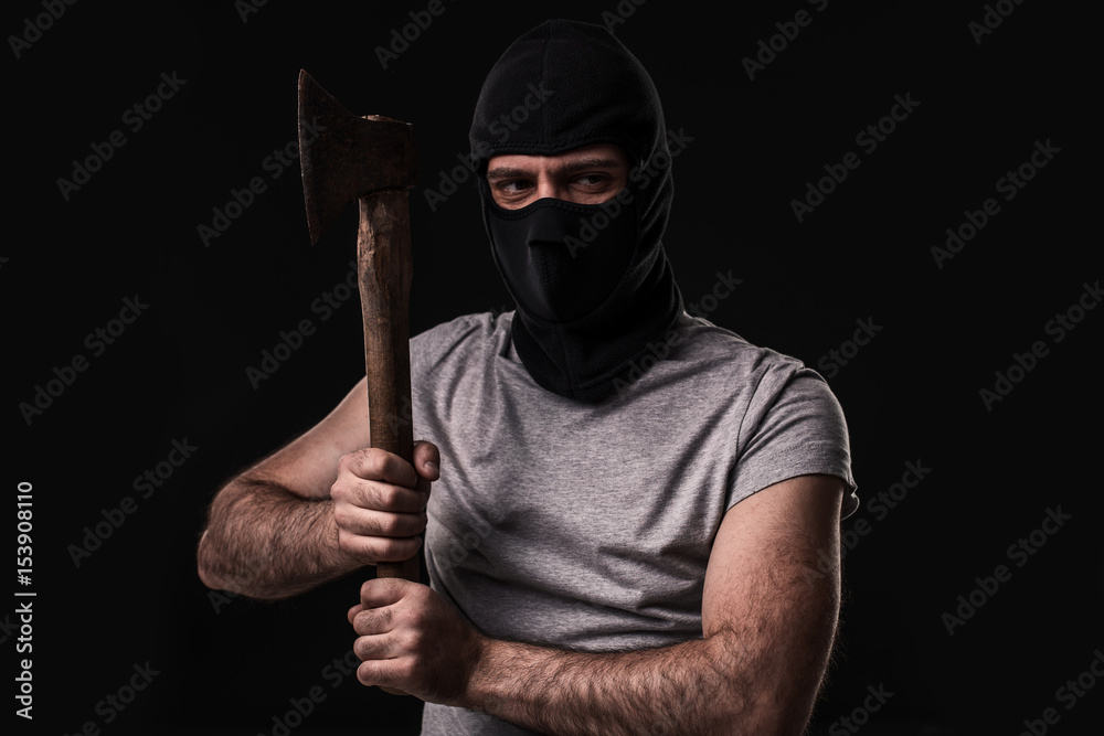 Bandit in black mask with hatchet on black background Bandit in black mask with hatchet on black background