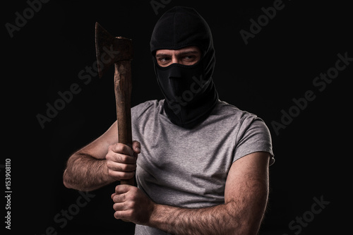 Bandit in black mask with hatchet on black background