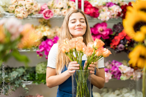 Female florist smelling a bunch of roses