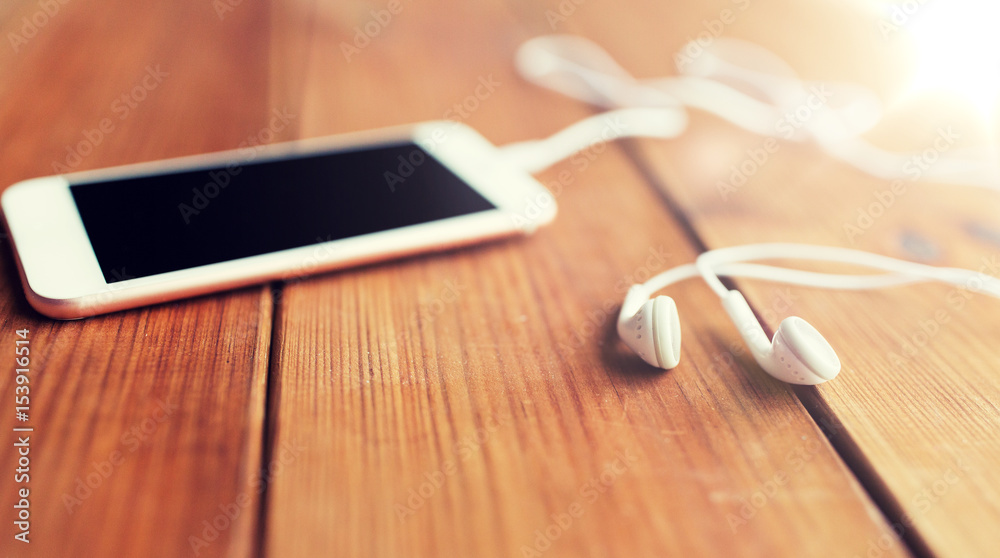 close up of blank smartphone and earphones on wood close up of blank smartphone and earphones on wood