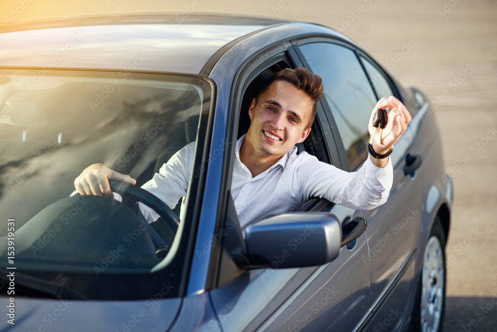 Happy buyer holding car keys inside his new vehicle
