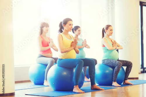 happy pregnant women exercising on fitball in gym
