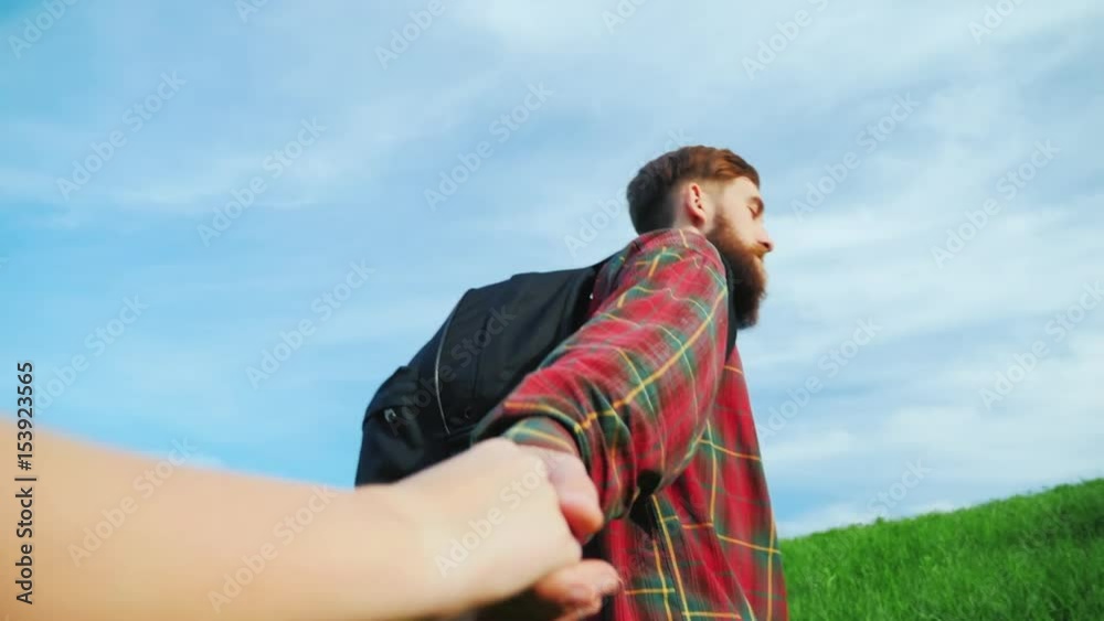 A young bearded man helps climb a mountain friend. Helping hand. A young bearded man helps climb a mountain friend. Helping hand.