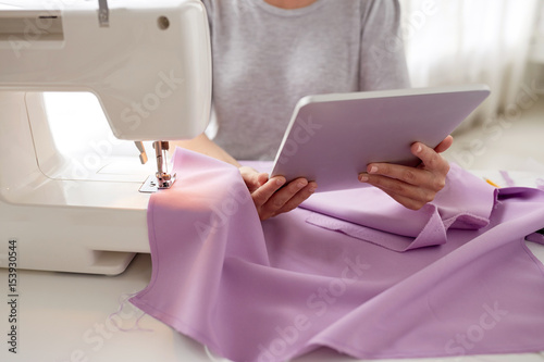 tailor with sewing machine, tablet pc and fabric © Syda Productions