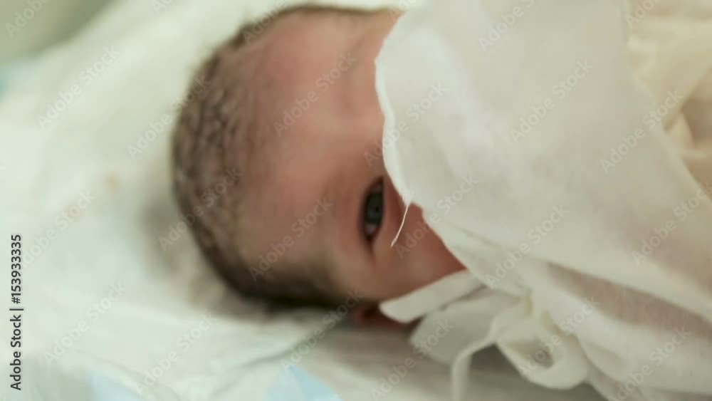 doctor puts a newborn with a clamp on the umbilical cord