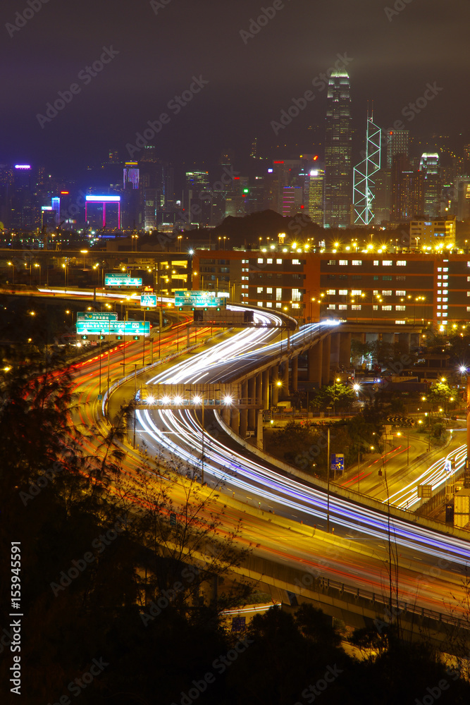 Light trail shot of the Tsing Kwai Highway in Hong Kong with buildings across the harbour on background