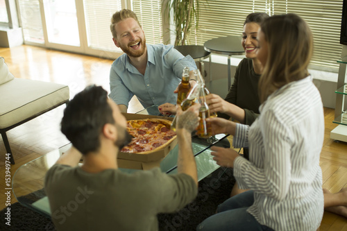 Young people eating pizza and drinking cider in the modern interior