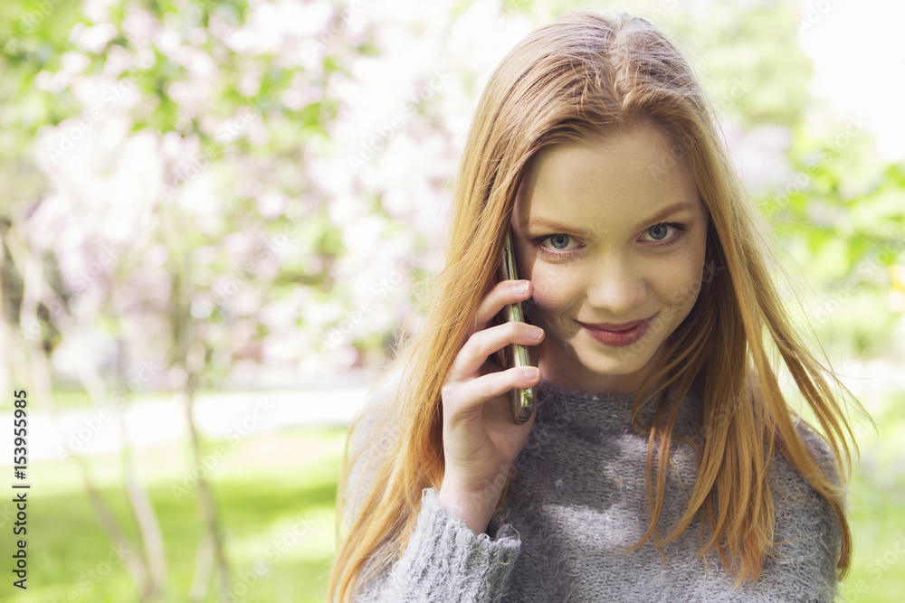 Beautiful red hair ginger slim young woman with fresh skin in casual outfit, making phone call. Sunny summer day in park (nature). Daylight Beautiful red hair ginger slim young woman with fresh skin in casual outfit, making phone call. Sunny summer day in park (nature). Daylight