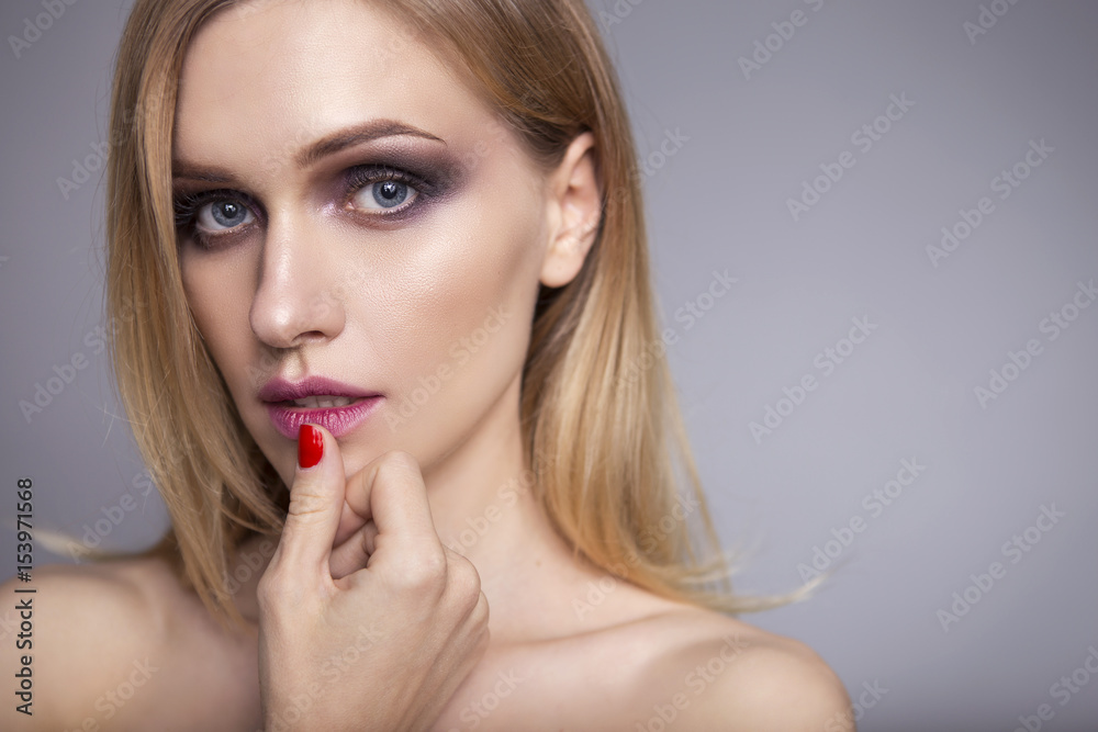 Blonde pretty woman in her 30th with fresh clean skin, smiling with smokey eyes and red lips make up on a neutral grey background. Casual posing Blonde pretty woman in her 30th with fresh clean skin, smiling with smokey eyes and red lips make up on a neutral grey background. Casual posing