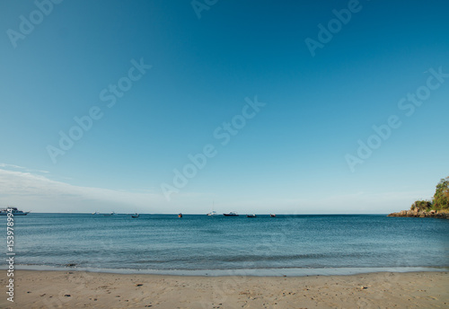 Sea boats sail along shore sandy beach. Landscape sea, ships and sandy beach